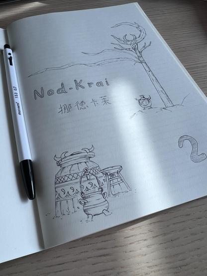 Front page of a notebook with a pen on it. The page displays the text “Nod-Krai” written in English and Chinese, the number “2” and drawings of pots and jars as well as a wooden pillar with a moon shaped decoration on top of it. 