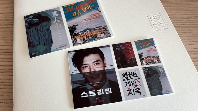 Two small sheets of photo paper on a white thin notebook. The first sheet contains two book covers and the second contains a movie poster and a grid of 4 small book covers. 