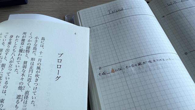 An opened book and opened notebook side by side. On the left of the picture, the right page of a Japanese novel is visible, the chapter is “prologue” and the first sentence starts with “island”. On the right of the picture, there’s the left page of a grid notebook with the title “Island” and the first sentence of the book has been handwritten with the word “island” in orange.