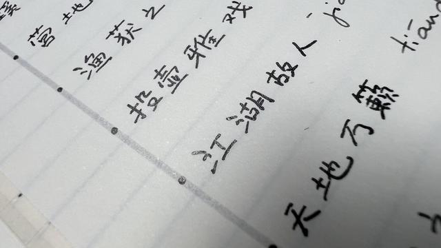Chinese characters handwritten on a notebook, the ink used is black but on some characters it looks like the ink is not fully dried, like it could easily smudge. 