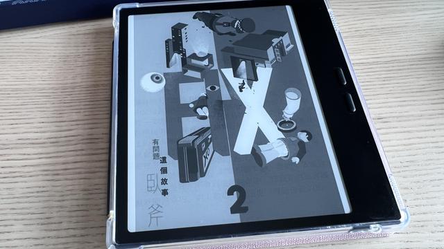 E-reader on a wooden table displaying a book cover on the screen. It has the word “FIX” written in big letters in the middle and a lot of small doodles (like buildings and people) around.